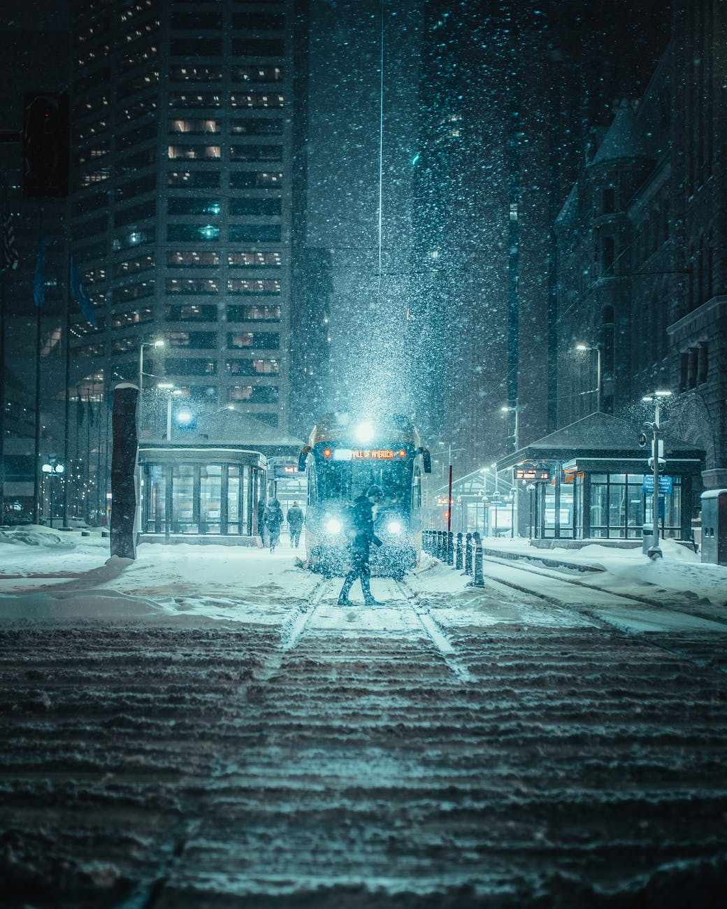紐約大雪紛飛的夜晚,一名行人獨自穿越積雪的電車軌道