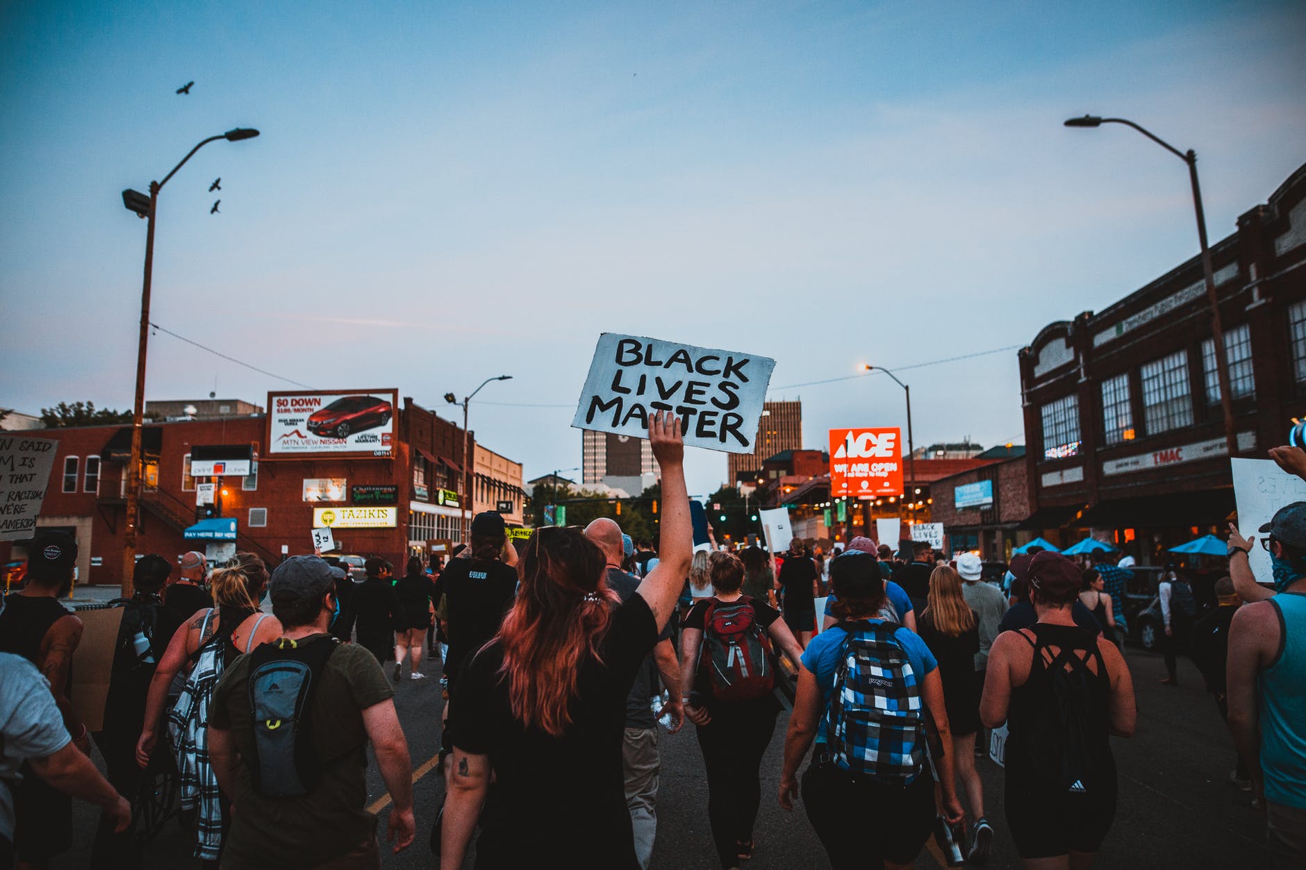 街頭遊行人群中,一人高舉寫著「BLACK LIVES MATTER」的手寫標語牌