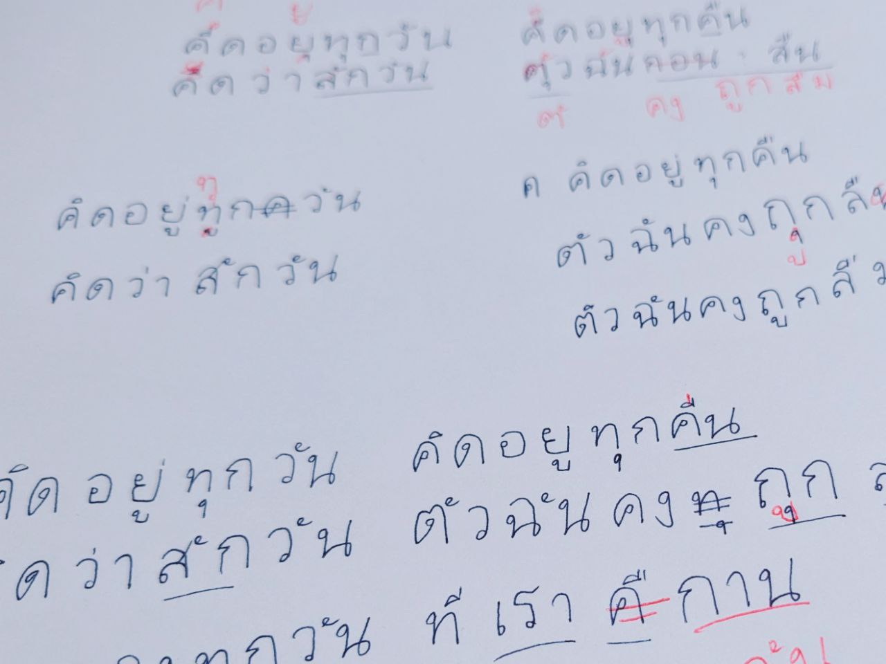 手寫筆記本反覆練習書寫泰文歌詞字形,並以紅筆標註修正錯誤