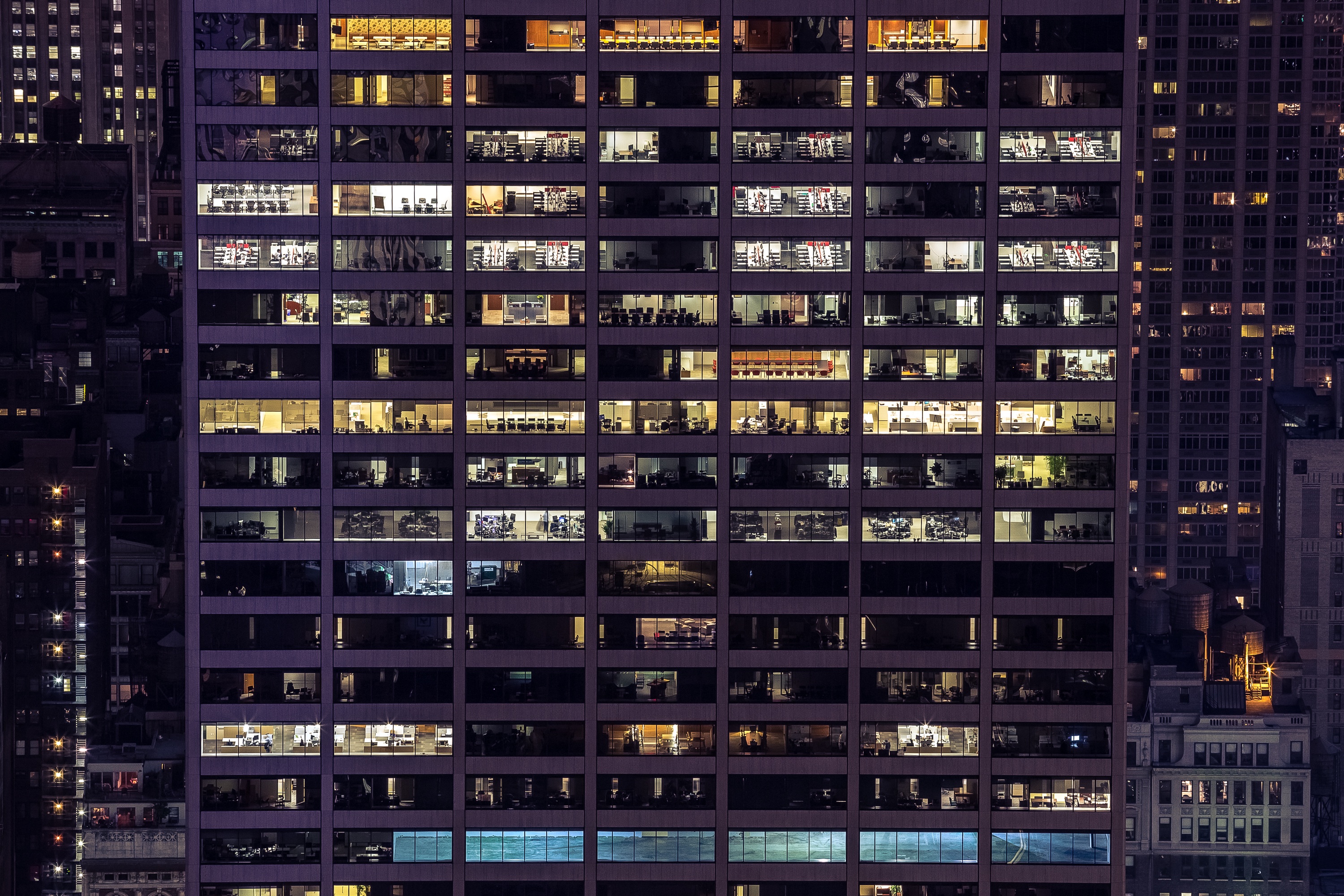 夜晚辦公大樓外觀,密集排列的窗格中透出各個辦公室的燈光
