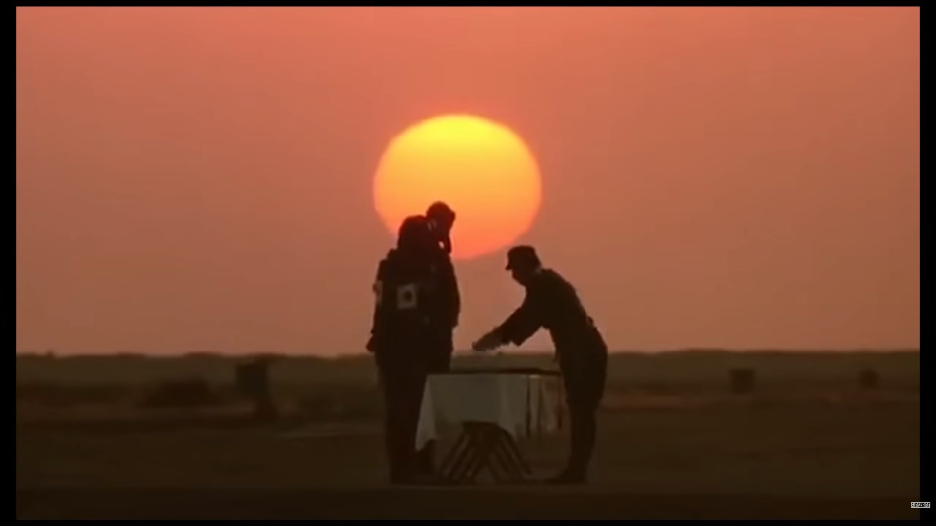 電影《太陽帝國》劇照:夕陽映照下,人物剪影站在戶外桌前